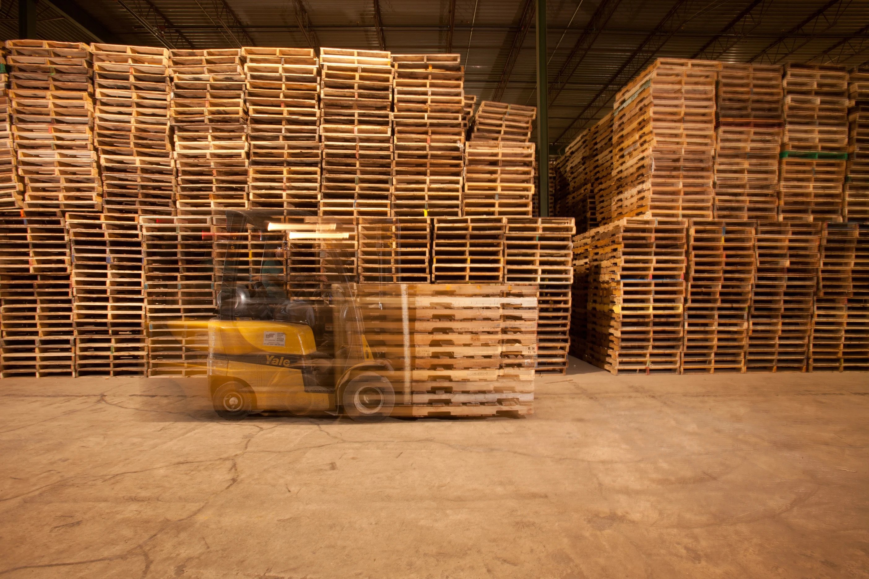 Forklift moving palletized commercial cargo inside a warehouse